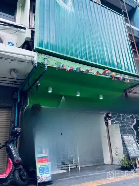 店屋 出租或出售在Khlong Toei, Bangkok - 多层店屋外立面，绿色金属板与卷闸门，临街人行道。