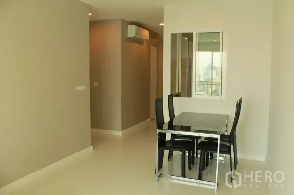 Condominium for rent or sale in Watthana, Bangkok - Minimal dining area with black table and four chairs beside a hallway and air conditioning.