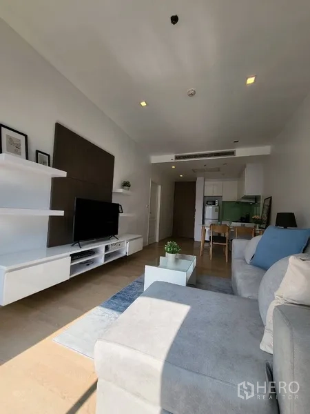 公寓 出租在Bangkok - 明亮客厅，L形沙发、电视墙与壁挂层架的现代公寓。