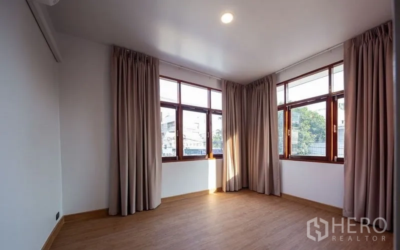 独立式住宅 出售在Chatuchak, Bangkok - 转角卧室，三面采光落地窗与木纹地面。