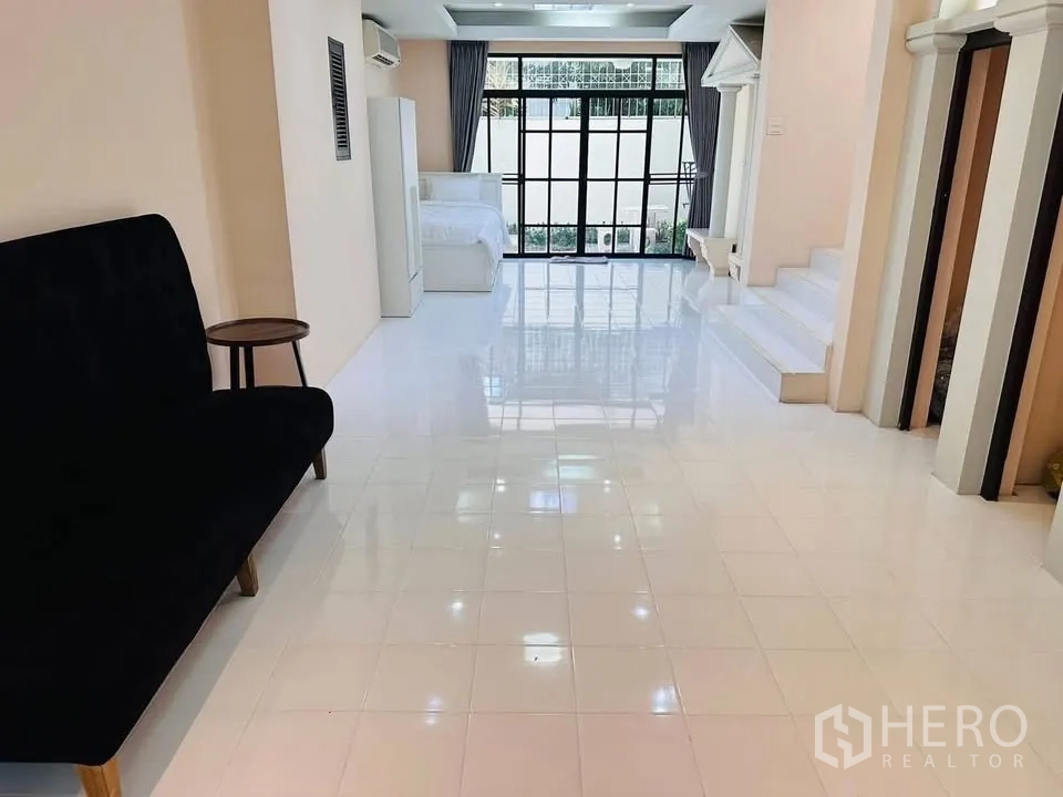 联排别墅 for rent - 一层开放空间，白色亮面地砖、沙发与通向室外的大玻璃门。