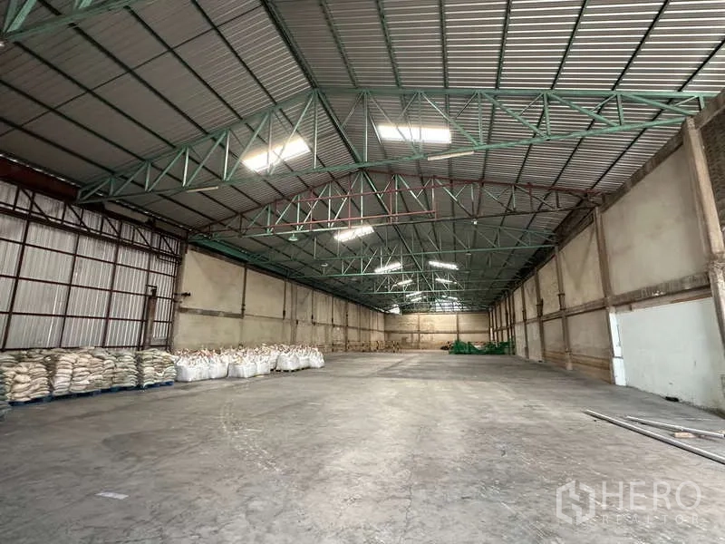 货栈 出租在Mueang Pathum Thani, Pathum Thani - 大跨距仓库分区，隔热屋顶，墙边有托盘货物。