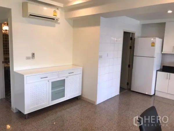 Condominium for rent in Watthana, Bangkok - Kitchen area with white sideboard, air conditioner and full-size refrigerator.