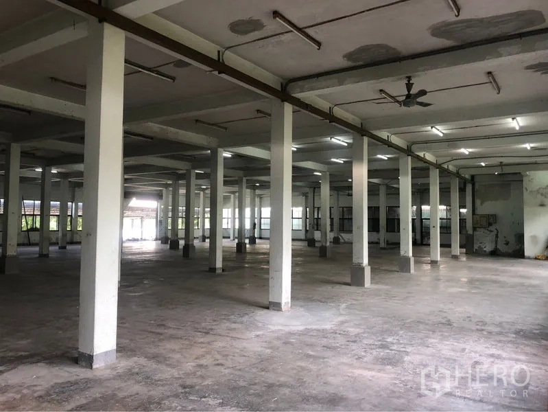 Office Space for rent in Bang Sao Thong, Samut Prakan - Industrial office interior with concrete floor, ventilation fans and fluorescent lights.