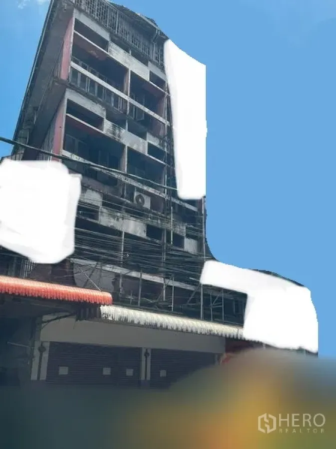 店屋 出租 - Bang Na 多层临街商铺外观，卷闸门与金属遮阳棚，晴朗蓝天下的建筑立面。