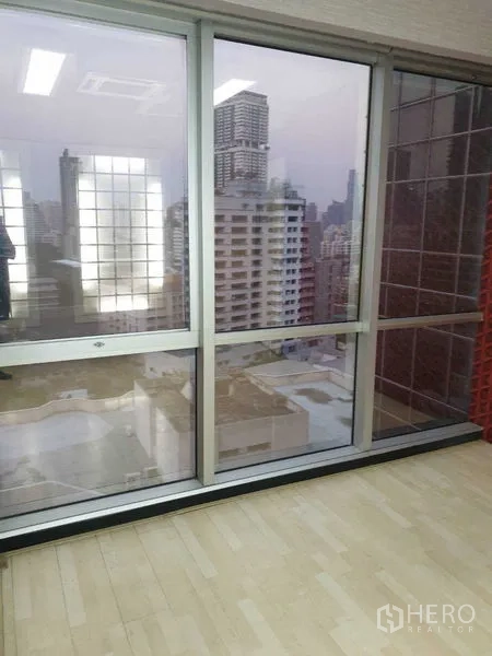 Office Space for rent - Sliding glass windows providing urban views and natural light in a compact office room.