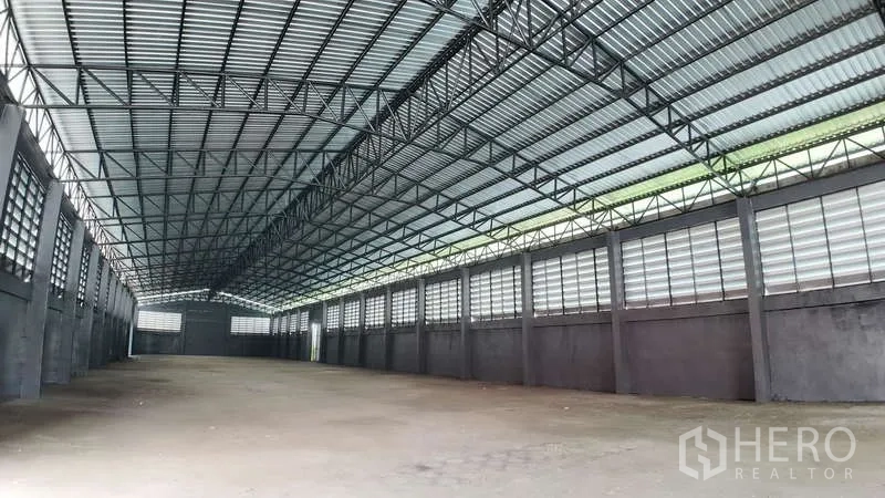 Warehouse for rent in Chachoengsao - Spacious warehouse interior with high steel‑truss roof, ventilated windows and open concrete floor.