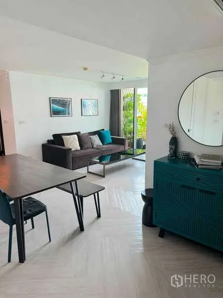 คอนโด ให้เช่าในKhlong Toei, Bangkok - ห้องนั่งเล่นมีตู้คอนโซลสีเขียวและกระจกกลม ข้างโซฟาและระเบียงสีเขียว