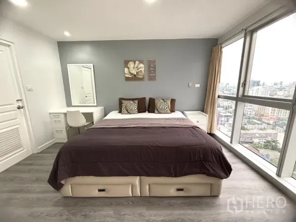 คอนโด ขายในKhlong Toei, Bangkok - ห้องนอนใหญ่สว่าง เตียงคิง ผนังเทา โต๊ะเครื่องแป้ง และหน้าต่างกระจกเต็มบานวิวเมือง