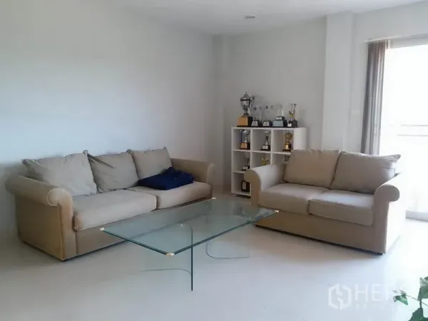 บ้าน ขายในSamut Prakan - ห้องนั่งเล่นสว่างโปร่ง โซฟาสีเบจสองชุดและโต๊ะกลางกระจกแบบมินิมอล.