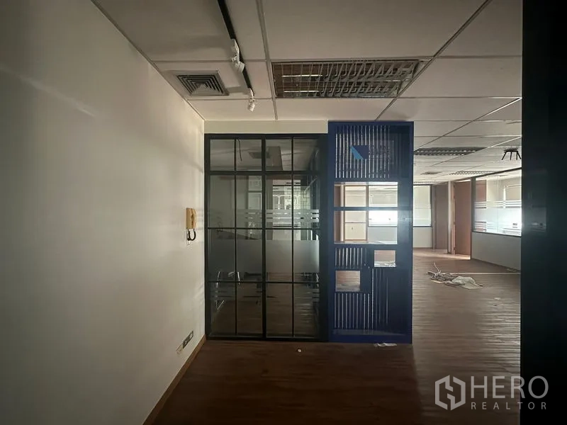 办公空间 出租在Bang Rak, Bangkok - 室内办公区，带磨砂条纹的玻璃隔间会议室，格栅天花与灯光空调，木纹地板。