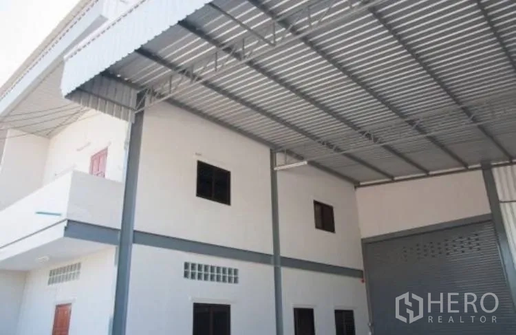 Warehouse for rent in Bang Phli, Samut Prakan - Metal roof canopy above the office facade and roller shutter entrance.