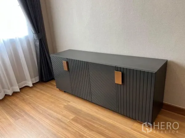 Detached House for sale in Mueang Pathum Thani, Pathum Thani - Modern black sideboard cabinet beside a curtained window on wooden floor