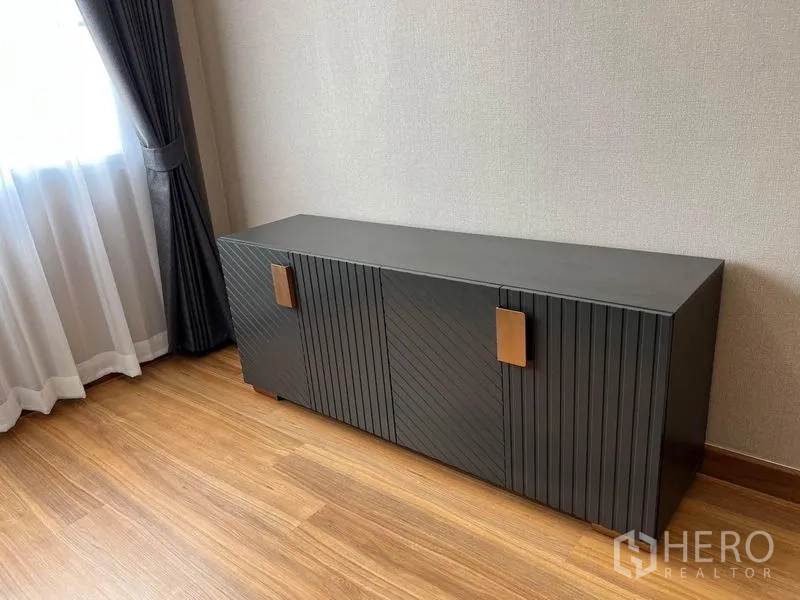 Detached House for sale in Mueang Pathum Thani, Pathum Thani - Modern black sideboard cabinet beside a curtained window on wooden floor