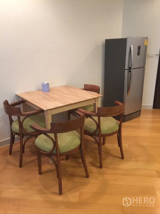 Condominium for rent in Bang Kho Laem, Bangkok - Dining corner with wooden table, four chairs and a stainless-steel refrigerator.
