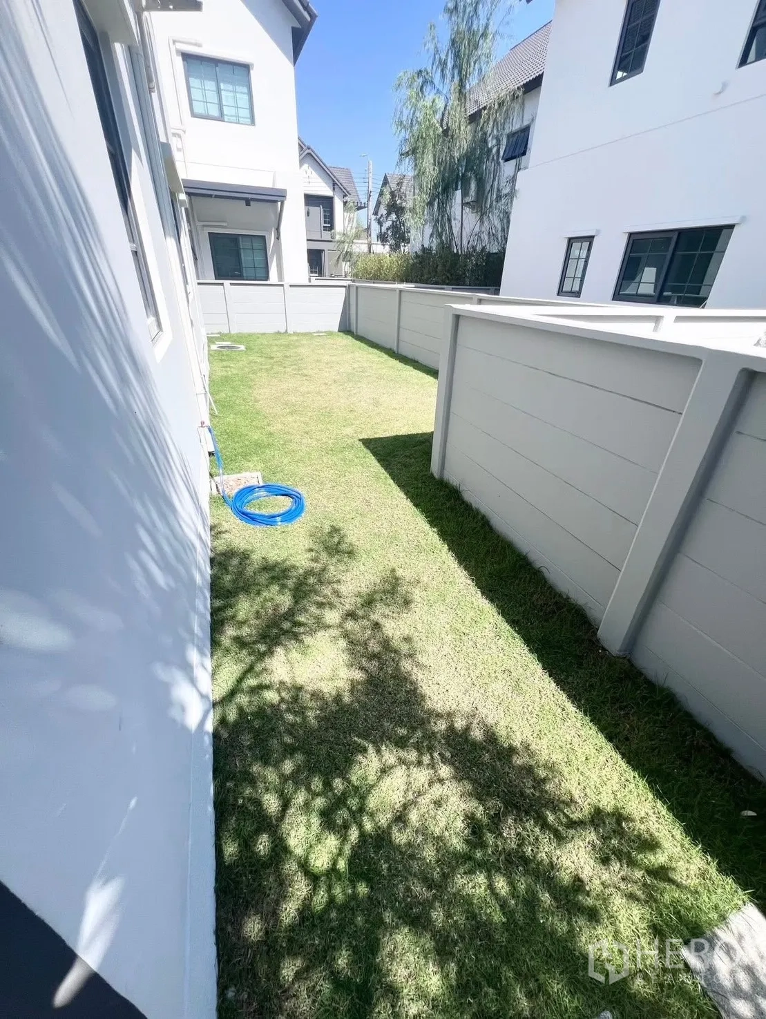 Detached House for rent in Bang Phli, Samut Prakan - Narrow side yard with grass lawn and tall privacy fence between houses.