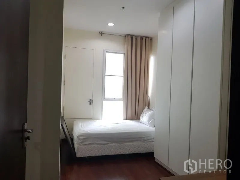 公寓 出租在Pathum Wan, Bangkok - 第二卧室带单人床、高柜衣橱与米色窗帘的窗户。