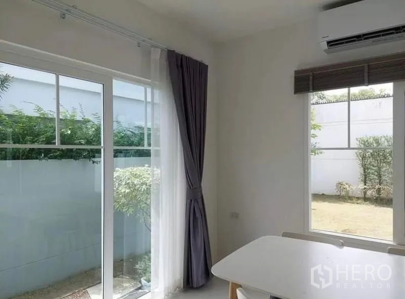 Detached House for rent in Bang Bo, Samut Prakan - Dining nook with corner windows, long curtains and views to the lawn garden.