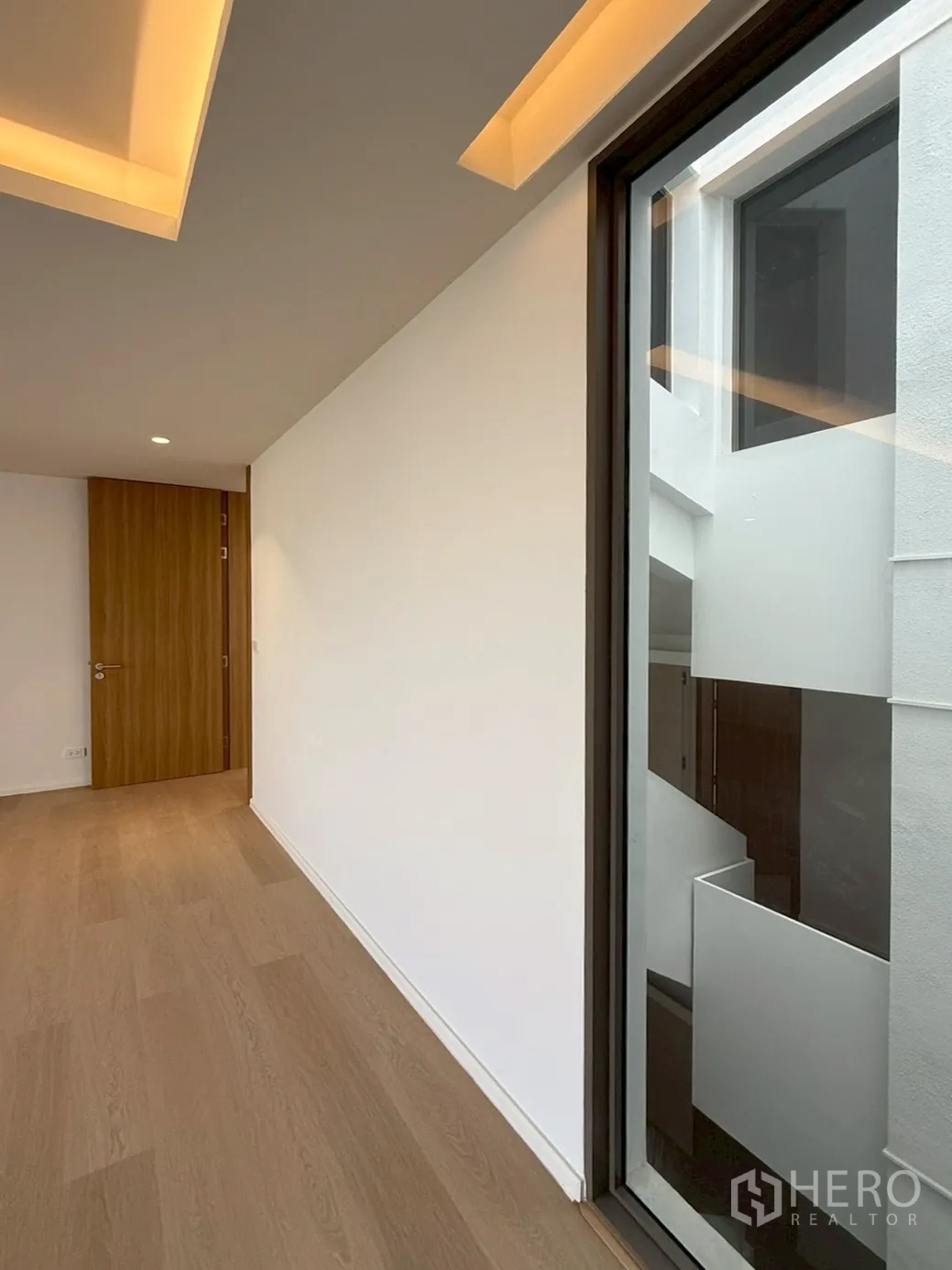 家庭办公室 for rent or sale in Watthana, Bangkok - 走廊铺木地板，窗向室内天井采光井。