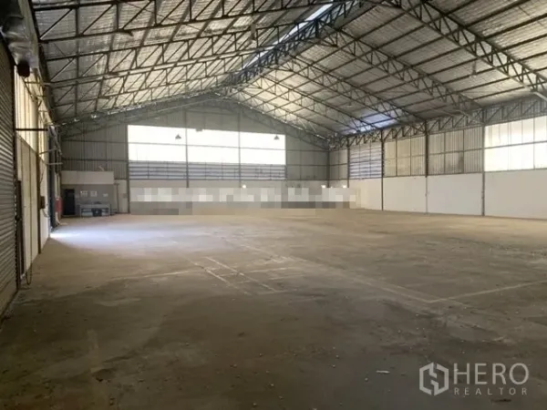 Warehouse for rent in Saphan Sung, Bangkok - Spacious warehouse interior with high steel truss roof, skylights, roller shutters and concrete flooring.