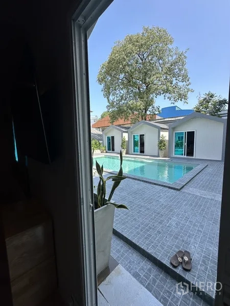 带办公室的家 出租在Suan Luang, Bangkok - 从门口望向泳池与灰色露台，大树成景。