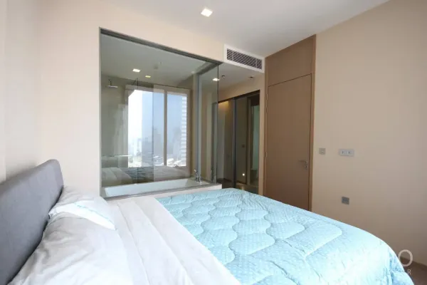 Condominium for rent in Watthana, Bangkok - Cozy bedroom with large window and glass wall connecting to the bathroom.