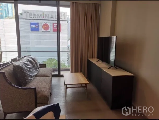 คอนโด ให้เช่าในWatthana, Bangkok - ห้องนั่งเล่นสว่างด้วยผนังกระจกเต็มบาน มีโซฟา ชั้นวางทีวี มองเห็นห้าง Terminal 21