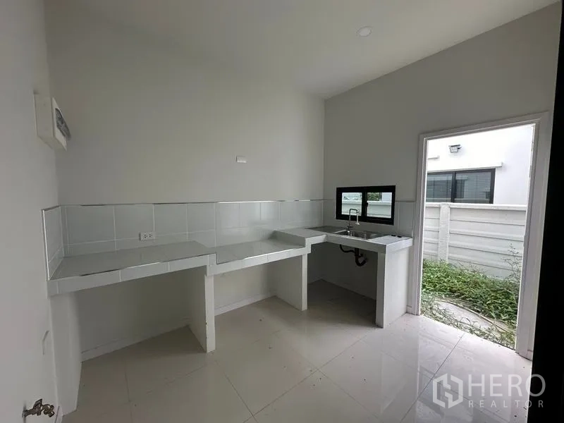 Detached House for sale in Khlong Sam Wa, Bangkok - Thai kitchen with countertops, sink and door to the side yard