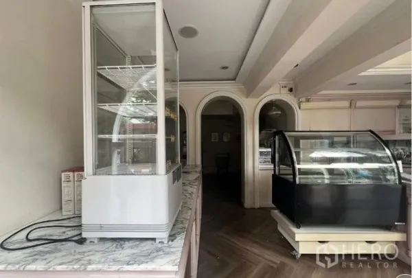 店屋 出租在Phaya Thai, Bangkok - 一层零售区，岩板台面、展示冷柜与拱形门洞。