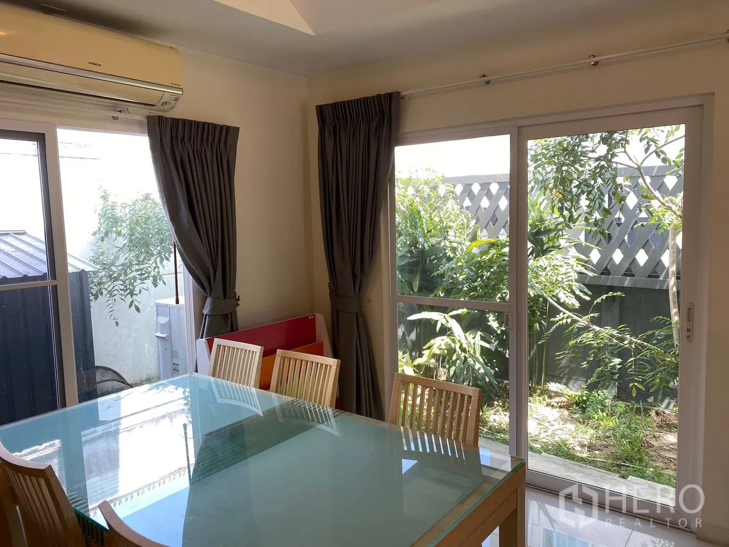 Detached House for rent in Prawet, Bangkok - Dining space with glass-top table and sliding doors to the garden.