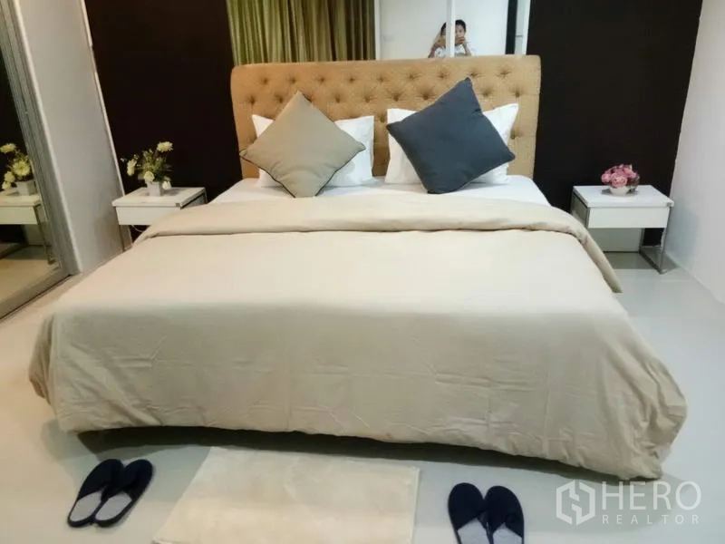Condominium for rent in Watthana, Bangkok - Cozy bedroom with upholstered headboard, beige bedding and mirrored wardrobe.