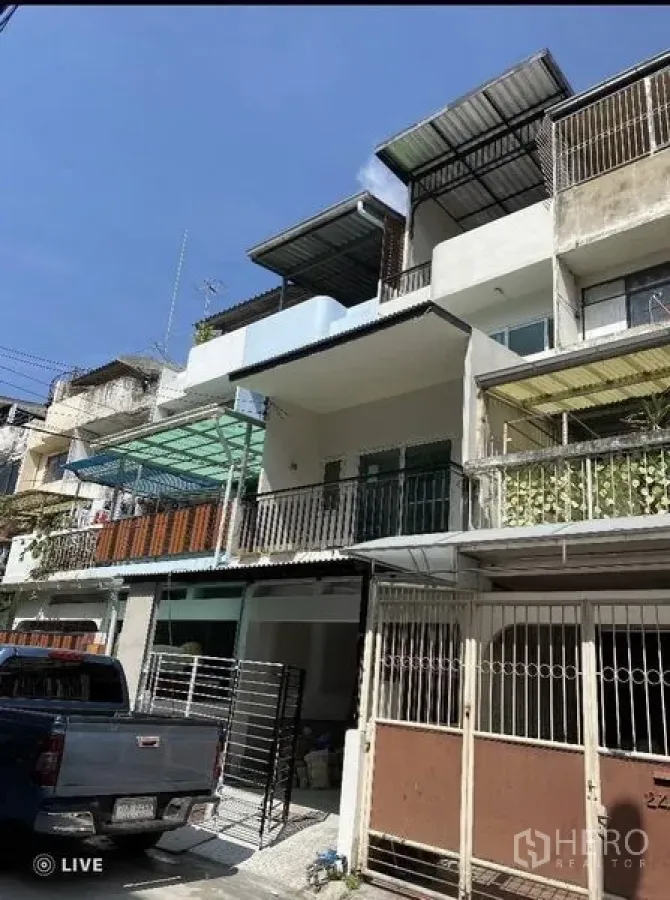 Townhouse for sale in Khlong Toei, Bangkok - Three-storey Ekkamai townhouse exterior with balconies, metal railings, and a covered carport.