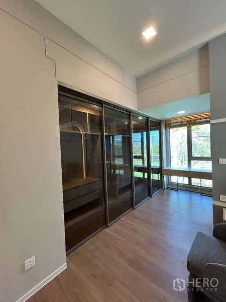 Detached House for rent in Saphan Sung, Bangkok - Walk-in closet corridor with glass wardrobes and a bright study nook by the window.
