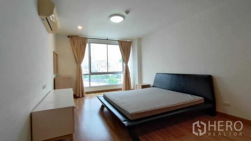 คอนโด ให้เช่าในKhlong Toei, Bangkok - ห้องนอนที่สองกว้าง เตียงแพลตฟอร์ม หน้าต่างบานใหญ่ วิวเมืองและผ้าม่านโทนเรียบ