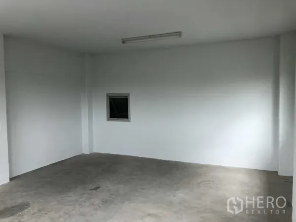 联排别墅 出售在Bang Bua Thong, Nonthaburi - 一楼开放式房间，白色墙面、混凝土地面与日光灯。