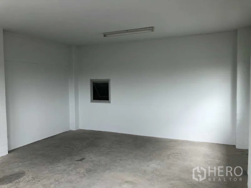 联排别墅 出售在Bang Bua Thong, Nonthaburi - 一楼开放式房间，白色墙面、混凝土地面与日光灯。