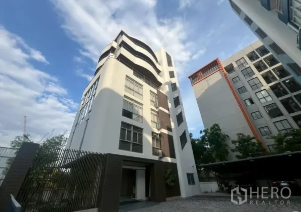 Office Space for rent in Prawet, Bangkok - Modern mid-rise office building in Prawet with curved facade and paved driveway under blue sky.