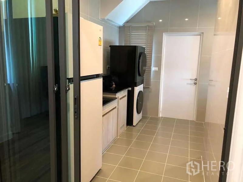 บ้าน ขายในBang Sao Thong, Samut Prakan - ครัวแยกปิดและโซนซักรีด มีตู้เย็น อ่างล้างจาน และเครื่องซักอบแบบตั้งซ้อนหลังประตูกระจก