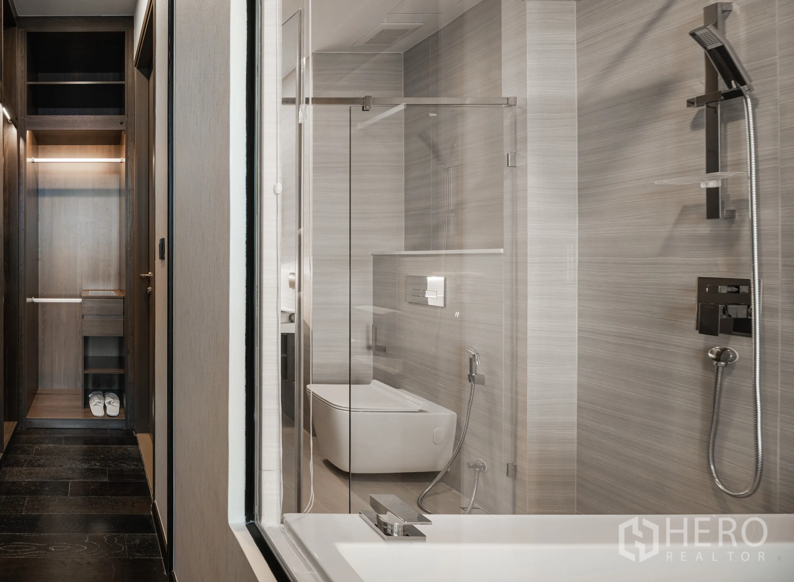 公寓 for rent in Watthana, Bangkok - 现代卫浴配玻璃淋浴间、浴缸、手持花洒与中性色墙砖，旁设衣柜空间。