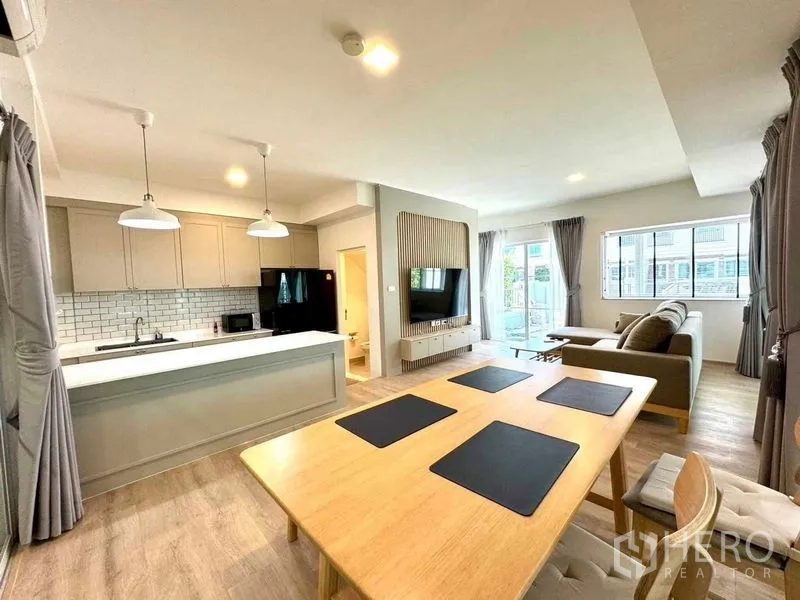 联排别墅 出租或出售在Prawet, Bangkok - 明亮的开放式客餐厅，带岛台厨房与电视背景墙的联排别墅室内。