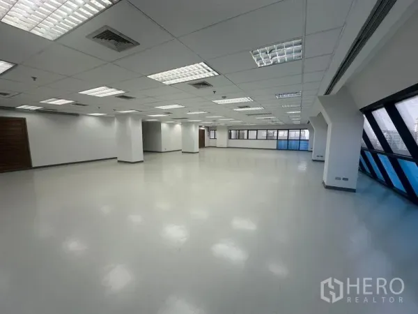 สำนักงาน ให้เช่าในPhaya Thai, Bangkok - ภายในสำนักงานกว้าง มีเสาหลายต้น ประตูไม้ และแถบหน้าต่างกระจกเอียงสีฟ้าตลอดแนว.