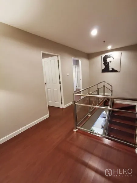 Condominium for rent or sale in Huai Khwang, Bangkok - Upper landing with wood floors and stainless stair railing leading to bedrooms.