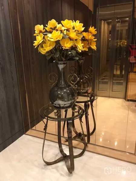 独立商业地产 出租在Chatuchak, Bangkok - 电梯旁镜面角落，放置黄色花束的装饰花瓶与小桌。