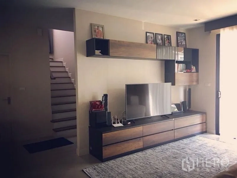 บ้าน ขาย - ผนังทีวีบิลท์อินและชั้นวางของติดกับบันไดในโซนนั่งเล่น