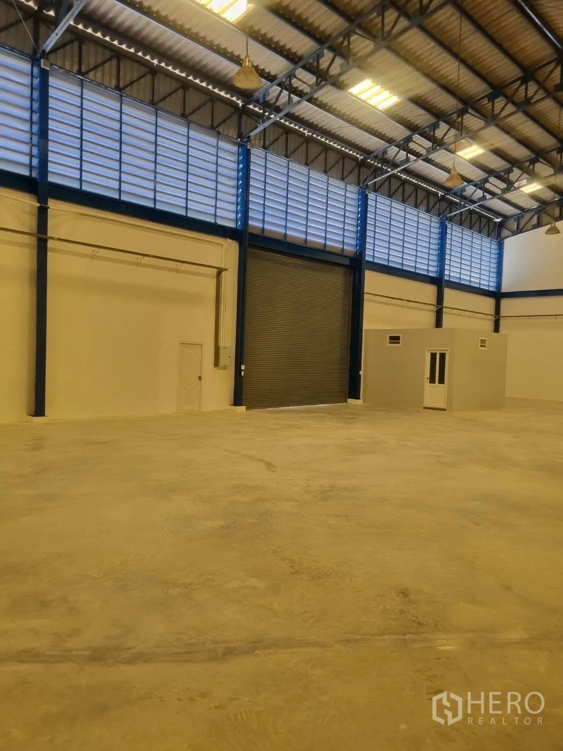 Warehouse for rent in Thepharak, Nakhon Ratchasima - Warehouse interior with large shutter, office cube, and clear floor area.