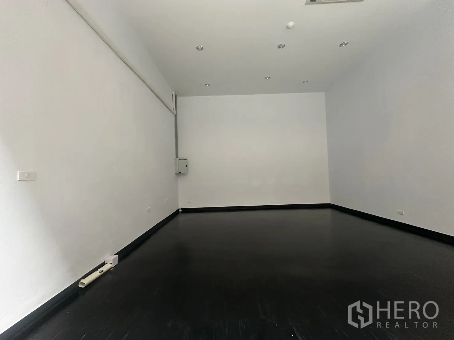 零售空间 for rent in Watthana, Bangkok - 白色墙面、深色地板、筒灯与电控箱的空置零售室内空间