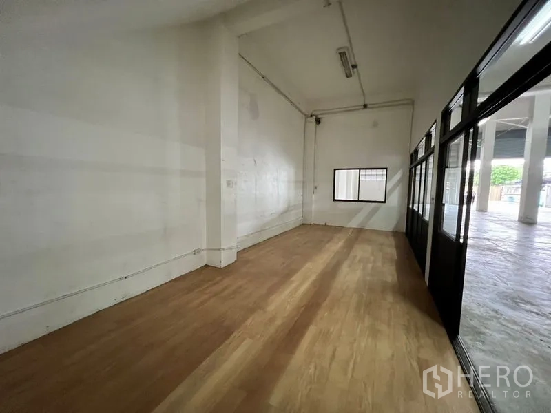 Warehouse for rent in Min Buri, Bangkok - Ground‑floor office room with wood‑look flooring and a window facing the warehouse.