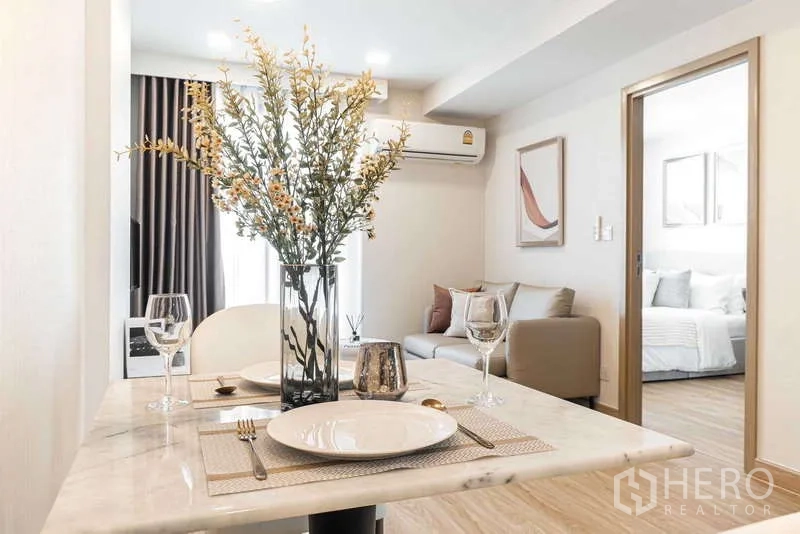 คอนโด ให้เช่า - โต๊ะอาหารจัดครบสำหรับสองที่พร้อมแจกัน มองไปยังโซนนั่งเล่น