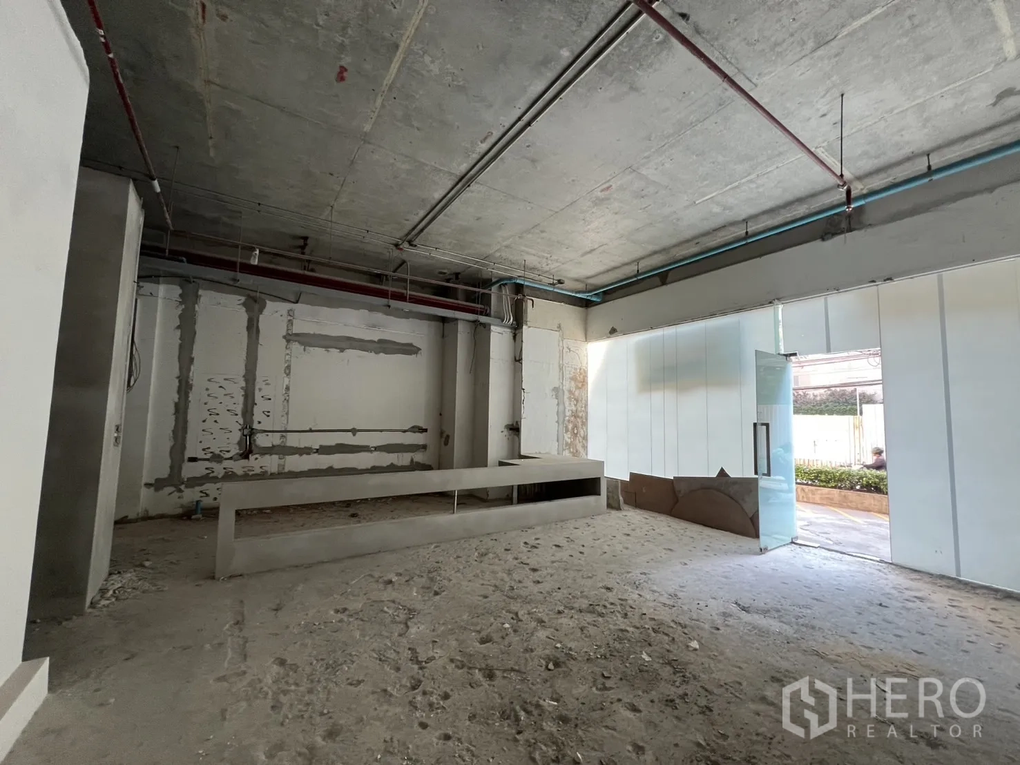 Retail Space for rent in Khlong Toei, Bangkok - Open-plan shell space with glass entrance and a built-in concrete counter base.