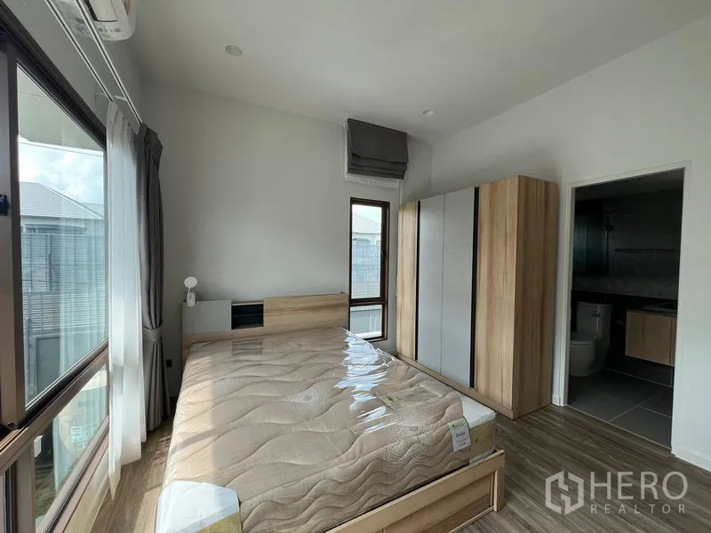 Detached House for rent in Bang Kapi, Bangkok - Bedroom with bed, wardrobes and ensuite bathroom entrance.